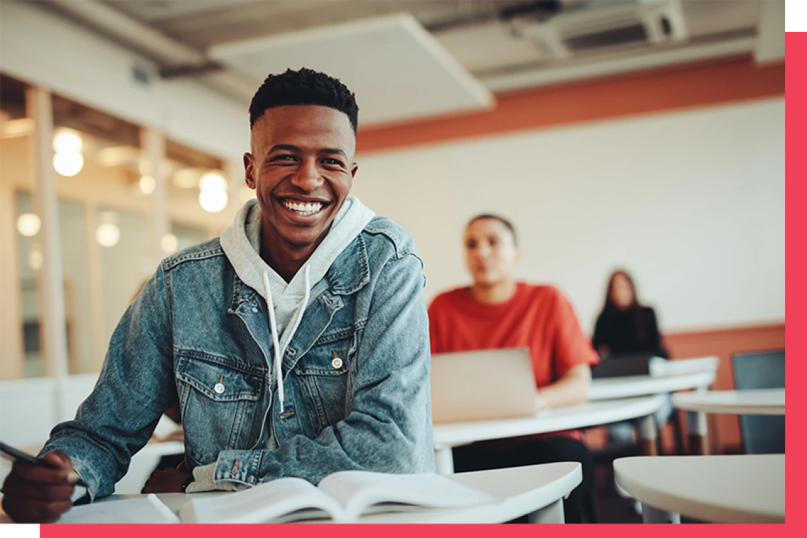 Student smiling while sitting at desk in classroom