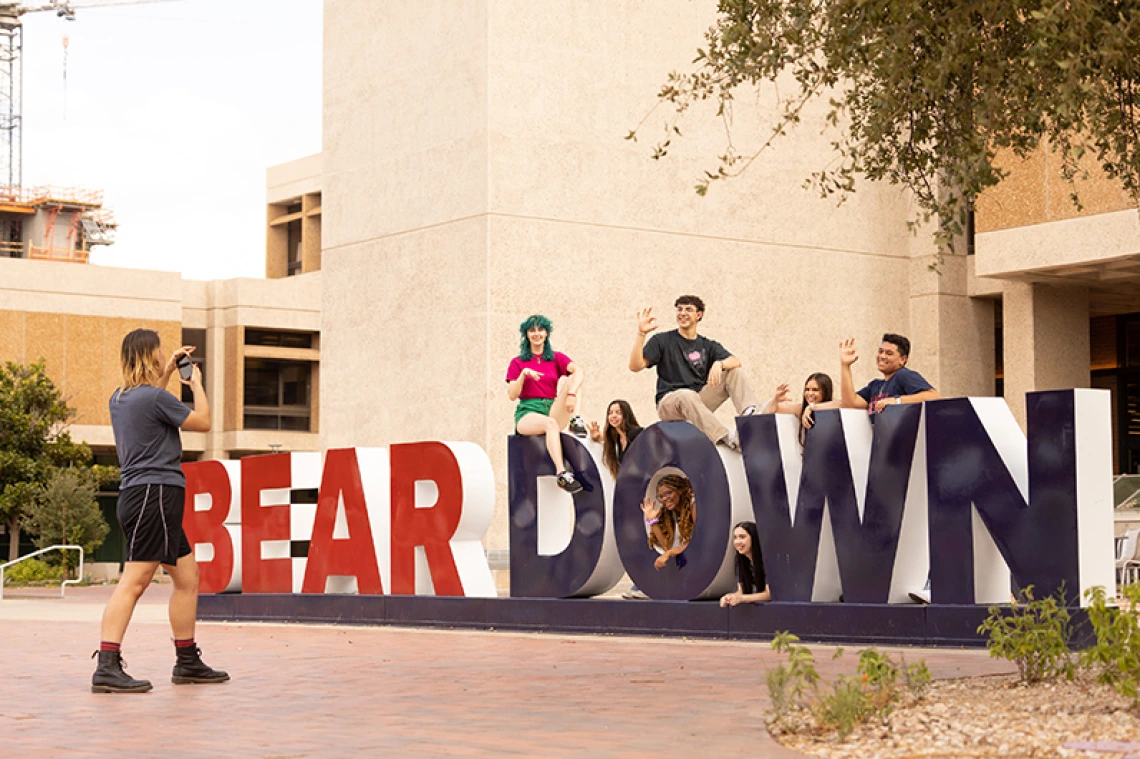 Group of students getting their photo taken on the bear down sign